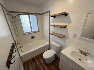 Full bathroom featuring toilet, vanity,  shower combination, and hardwood / wood-style floors