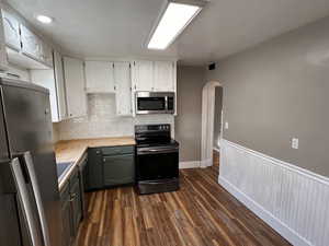 Kitchen featuring tasteful backsplash, dark wood-type flooring, stainless steel appliances, white cabinets, and wood counters