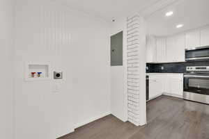 Kitchen with stainless steel appliances, dark hardwood / wood-style flooring, white cabinetry, and electric panel