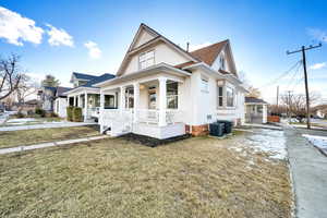 View of front facade with covered porch, a front yard, and central AC