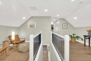 Hallway with lofted ceiling and light wood-type flooring