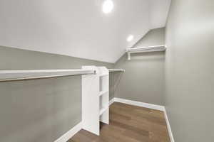 Spacious closet with vaulted ceiling and dark hardwood / wood-style flooring