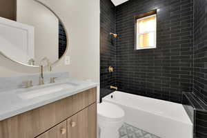 Full bathroom with tiled shower / bath combo, vanity, and toilet