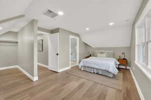 Bedroom featuring vaulted ceiling, connected bathroom, and light wood-type flooring