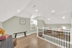 Hall with vaulted ceiling and light hardwood / wood-style floors