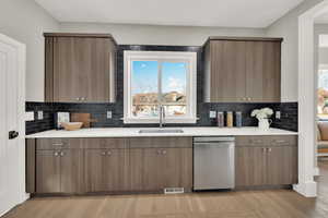 Kitchen featuring light hardwood / wood-style floors, dishwasher, backsplash, and sink