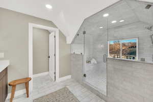 Bathroom with vaulted ceiling, tile patterned flooring, a shower with shower door, and vanity