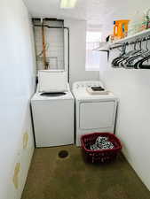 Clothes washing area featuring a textured ceiling and separate washer and dryer