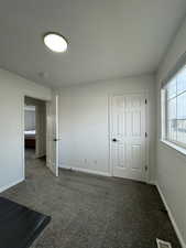 Unfurnished bedroom featuring a textured ceiling and dark colored carpet