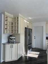 Kitchen with light stone counters, a textured ceiling, dark hardwood / wood-style floors, and stainless steel fridge with ice dispenser