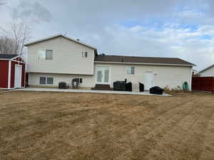 Back of house with a lawn, a shed, a patio area, and central AC