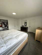 Bedroom with a closet, a textured ceiling, and dark colored carpet