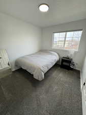 Bedroom featuring a textured ceiling and dark carpet