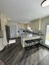 Kitchen featuring white appliances, a kitchen bar, sink, dark hardwood / wood-style floors, and kitchen peninsula