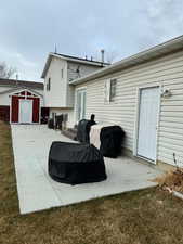 Rear view of house with a patio area, a storage shed, and a lawn