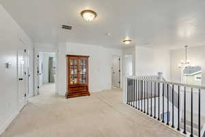 Hall with a notable chandelier and light colored carpet