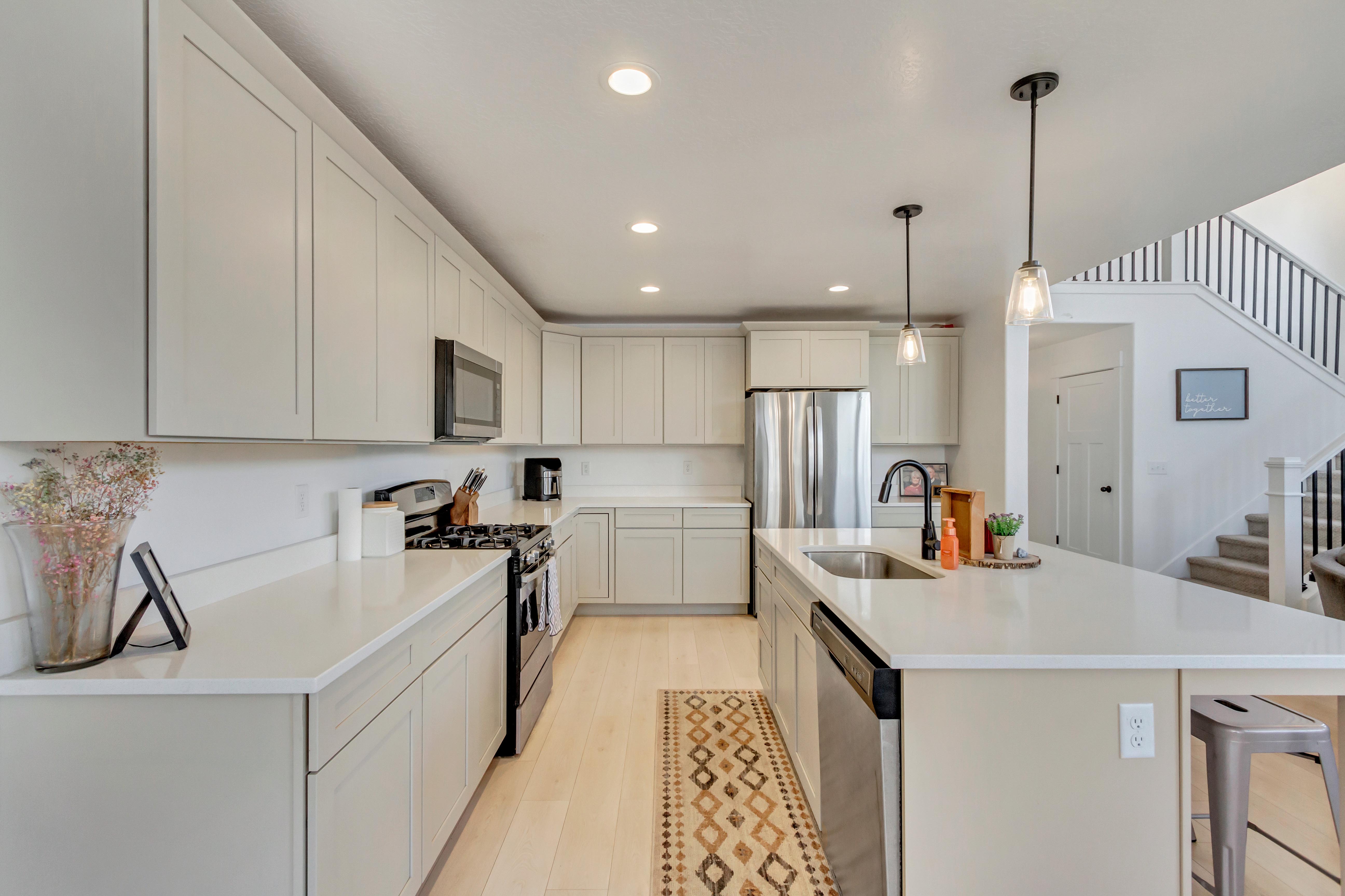 Kitchen featuring light hardwood / wood-style flooring, an island with sink, sink, decorative light fixtures, and appliances with stainless steel finishes