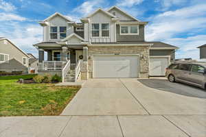 View of front facade featuring a porch, a front yard, and a garage