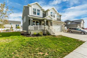 View of front facade featuring a front yard, a porch, and a garage