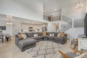 Living room with light hardwood / wood-style floors, a towering ceiling, and a chandelier