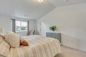 Bedroom featuring vaulted ceiling and light colored carpet