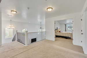 Hall with a chandelier, carpet flooring, and a textured ceiling