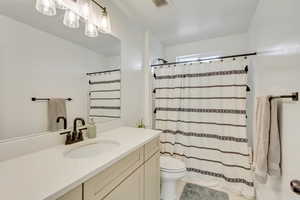 Bathroom with vanity, curtained shower, toilet, and tile patterned floors