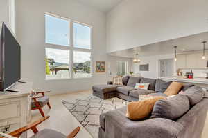 Living room featuring a high ceiling, a notable chandelier, and light hardwood / wood-style floors