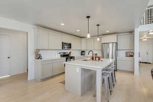 Kitchen featuring sink, an island with sink, stainless steel appliances, and light hardwood / wood-style floors