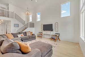 Living room featuring light hardwood / wood-style flooring, a chandelier, and a high ceiling