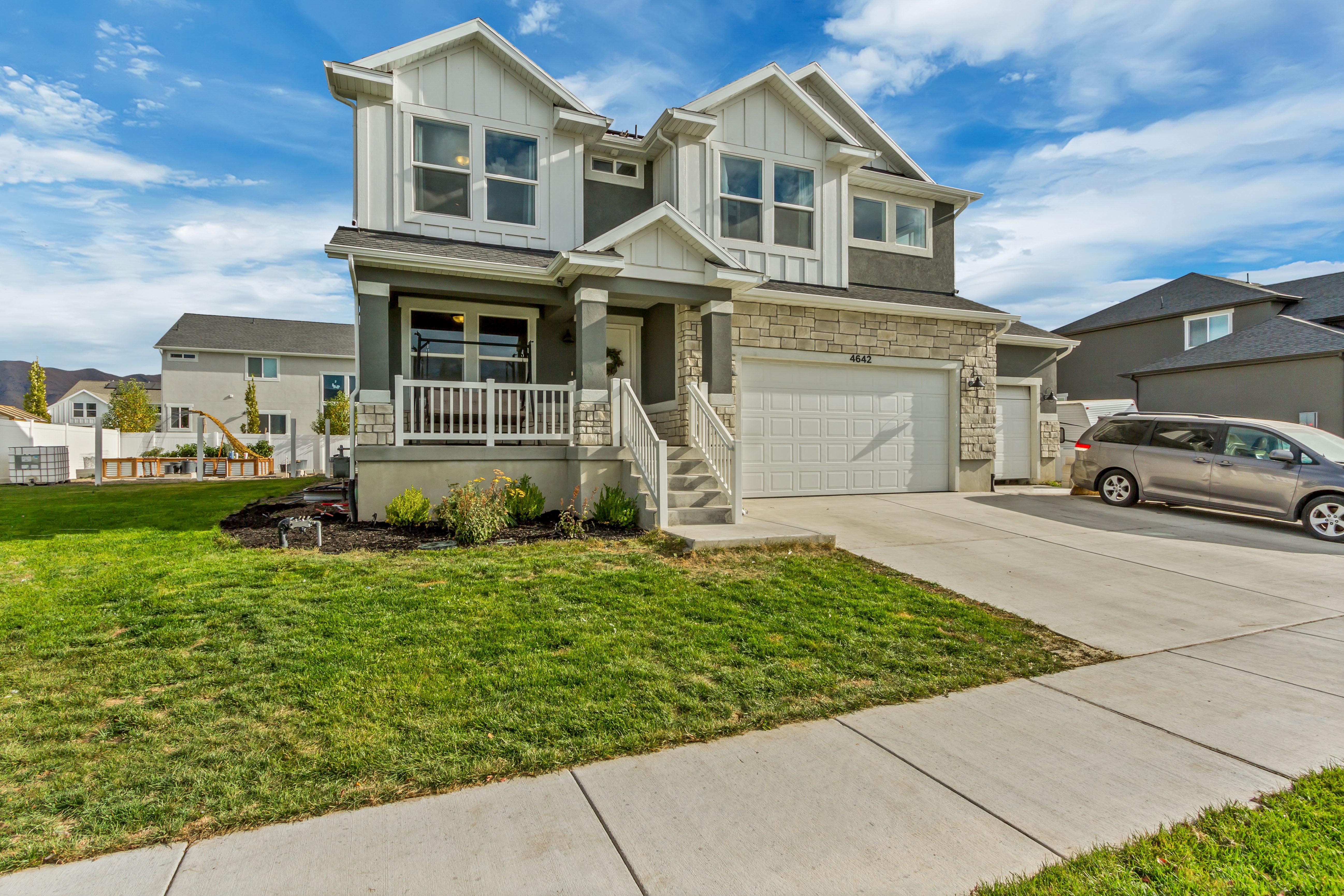 View of front of property featuring a porch, a front yard, and a garage