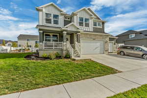 View of front of property featuring a porch, a front yard, and a garage