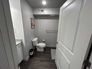 Bathroom with toilet, hardwood / wood-style floors, and vanity