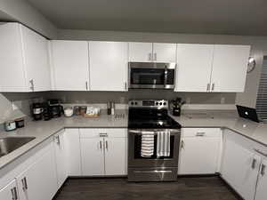 Kitchen featuring white cabinets, dark hardwood / wood-style floors, sink, and stainless steel appliances