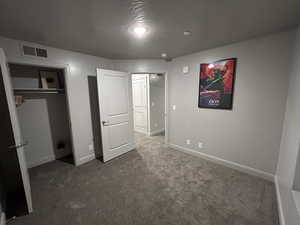 Unfurnished bedroom with a textured ceiling, a closet, and carpet flooring