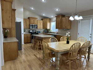 Dining room just off the kitchen with a notable chandelier, light hardwood / wood-style floors, and lofted ceiling