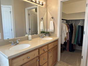 Master bathroom featuring tile patterned flooring, double vanity, and a walk in closet