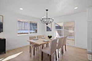 Dining room with a textured ceiling, an inviting chandelier, and light wood-type flooring