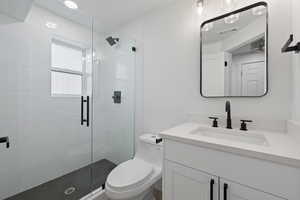 Bathroom featuring toilet, walk in shower, and vanity