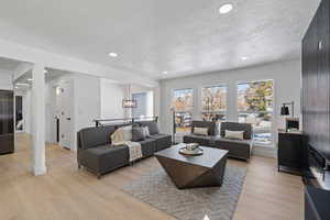 Living room featuring light hardwood / wood-style floors, a textured ceiling, and an inviting chandelier