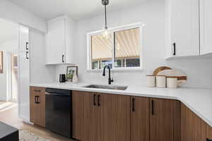 Kitchen with white cabinetry, light hardwood / wood-style floors, dishwasher, pendant lighting, and sink