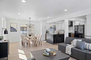 Living room with sink, a textured ceiling, light hardwood / wood-style flooring, and an inviting chandelier