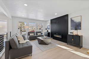 Living room with a textured ceiling, light hardwood / wood-style flooring, and a large fireplace