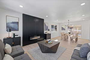 Living room with light wood-type flooring, an inviting chandelier, a textured ceiling, and a fireplace