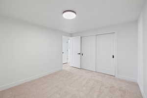 Unfurnished bedroom with light colored carpet and a closet