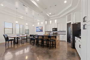 Kitchen featuring white cabinets, a raised ceiling, and stainless steel refrigerator