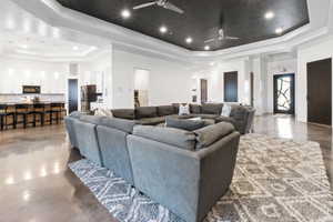 Cinema room with ceiling fan, a towering ceiling, a tray ceiling, and concrete floors