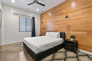 Bedroom featuring ceiling fan and wooden walls