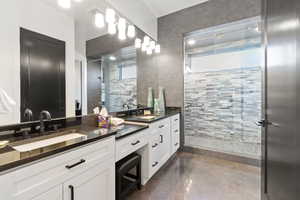 Bathroom with vanity, tile walls, plenty of natural light, and concrete flooring