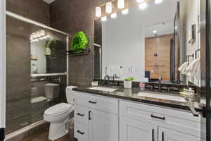 Bathroom featuring toilet, vanity, tile walls, and an enclosed shower